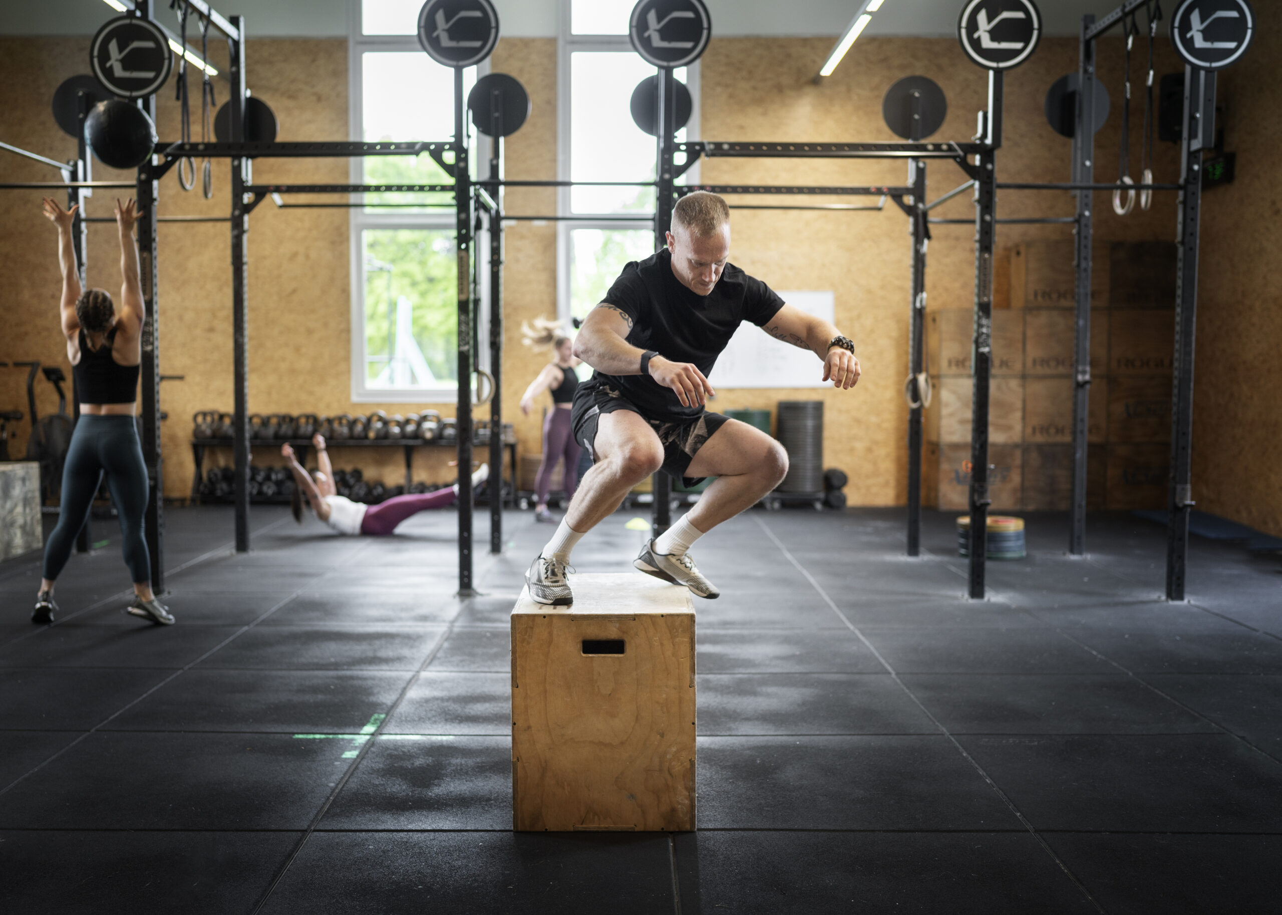 uomini e donne che svolgono un allenamento di crossfit per rimanere in forma Uomini e donne che sia allenano per mostrare che esercizi svolgere in una palestra di crossfit vicino a me